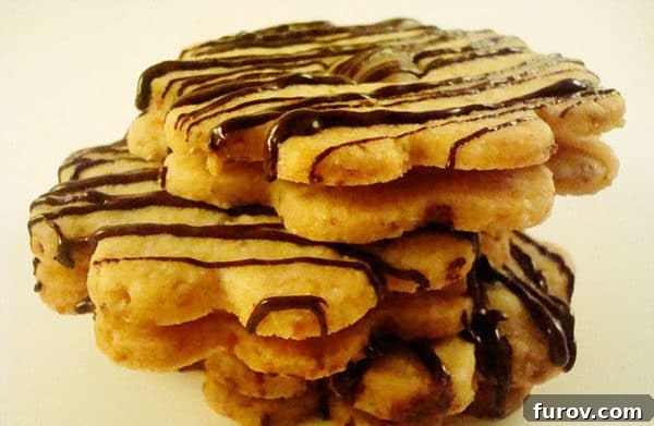Stack of flower shaped shortbread cookies with chocolate drizzle.