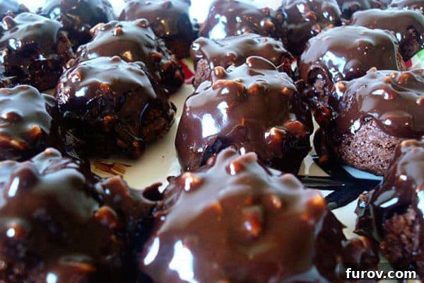 Close-up of freshly glazed Chocolate Toffee Brownie Bites on a white platter, highlighting the texture.