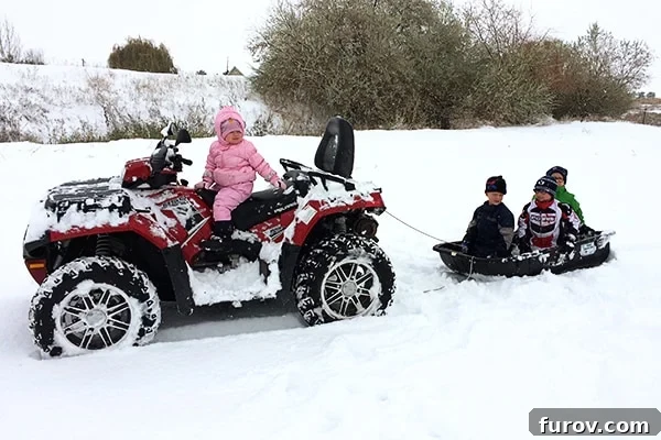 Children happily sledding in the snow, pulled by a 4-wheeler, after school was cancelled due to heavy snowfall and a heating outage.