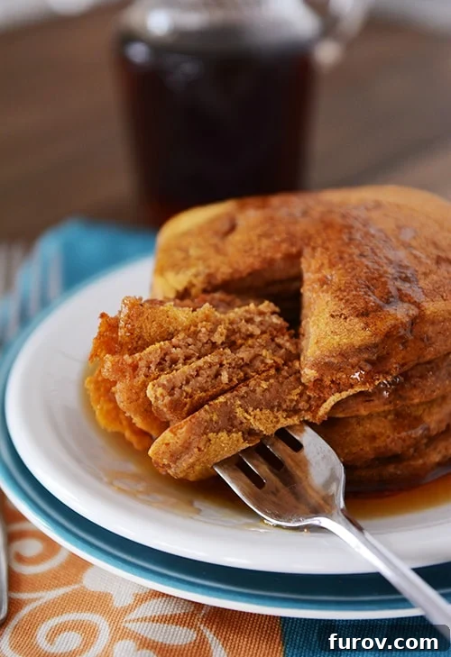 Flawless Pumpkin Pancakes 2 A big stack of pumpkin pancakes with a bite getting taken out of all of them.