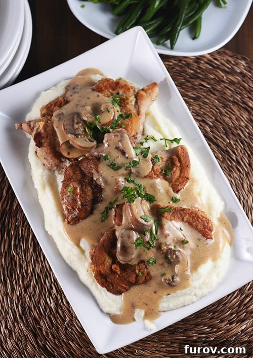 Smothered Golden Pork with Velvety Cauliflower Mash 4 Delicious crispy pork cutlets over a bed of mashed potatoes, topped with a flavorful brown mushroom sauce.