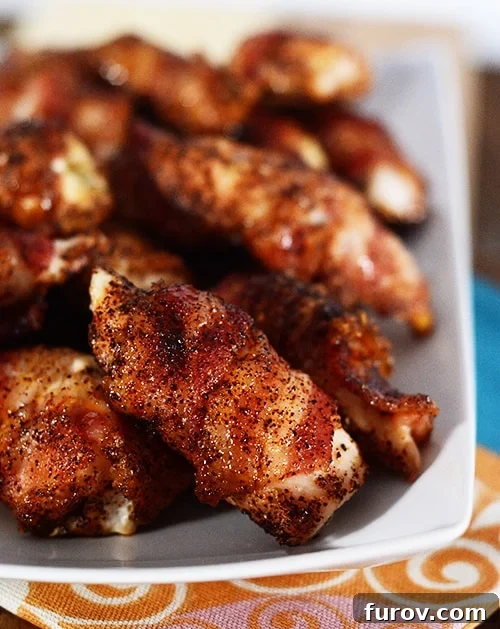 Anytime Bacon Chicken Bites 2 A white platter showcasing perfectly cooked bacon-wrapped chicken bites, glistening with a sweet and savory glaze.