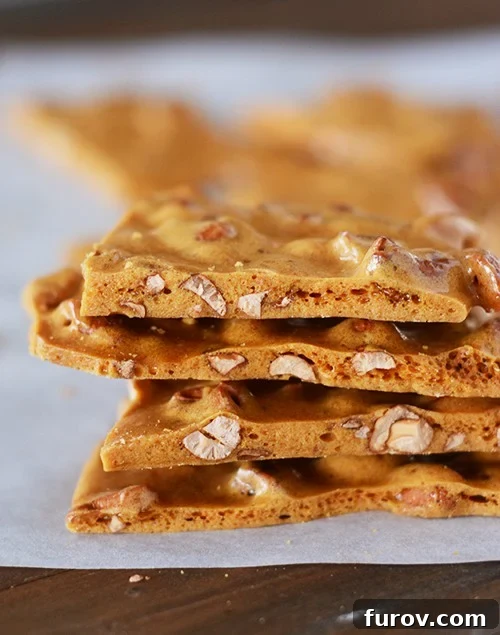 Stacked maple cashew brittle pieces on a piece of parchment paper, highlighting its golden color and crunchy texture.