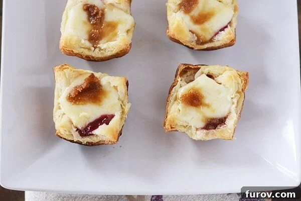 Top view of four perfectly golden-brown puff pastry baked brie bites, ready to be enjoyed as a delightful appetizer or snack.