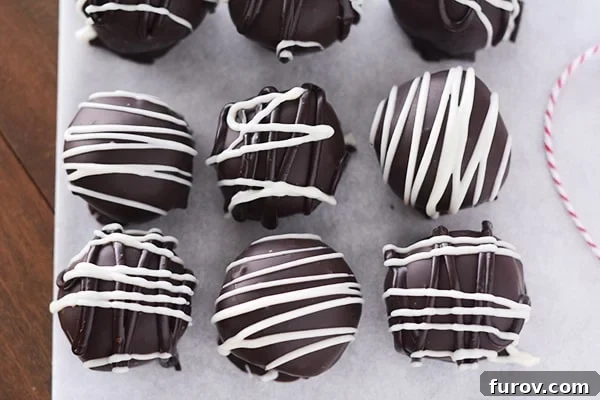 Spiced Gingerbread Chocolate Chip Cake Truffles 3 Top view of white chocolate drizzled chocolate gingerbread truffles on a piece of parchment paper, arranged and ready for serving.
