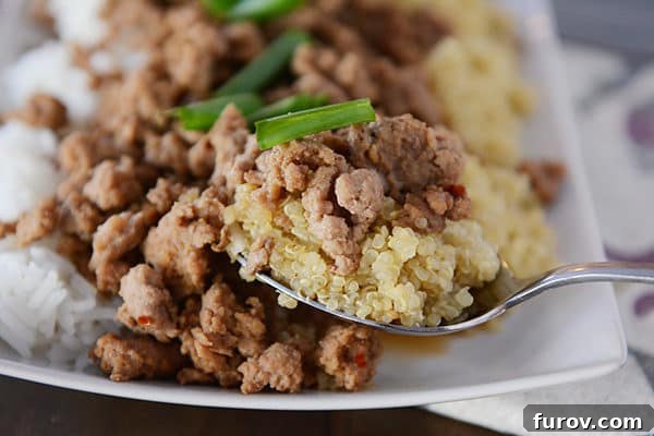 A scoop of cooked quinoa and beef over a tray with more beef and cooked rice.