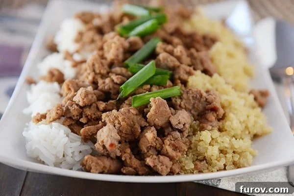 A white platter with half cooked white rice and half quinoa, topped with cooked beef.