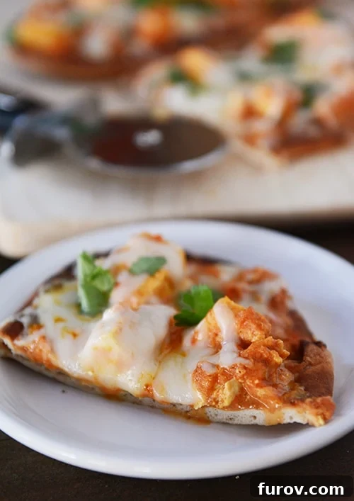 Easy 20 Minute Chicken Tikka Pizzas 2 A perfectly broiled slice of chicken tikka naan pizza, garnished with fresh cilantro, resting on a white plate, ready to be enjoyed.