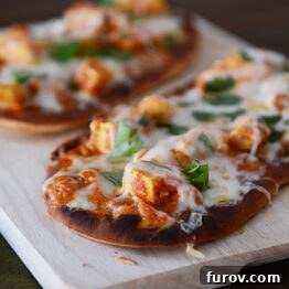 Easy 20 Minute Chicken Tikka Pizzas 4 A smaller image of two cheesy chicken tikka pizzas on a cutting board, perfect for a recipe card.