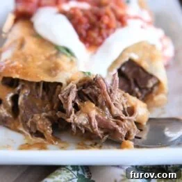 Two enchiladas on white plate with bite of enchilada on fork.