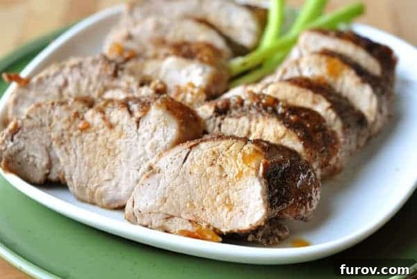 Thick slices of perfectly cooked brown sugar spiced pork loin on a white plate, beautifully arranged and garnished with fresh herbs, ready to be served.