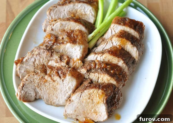 Top-down view of a serving of sliced brown sugar spiced pork loin medallions, artfully arranged on a white plate and generously drizzled with the savory glaze, accompanied by a complementary side dish.