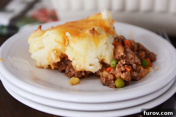 Rustic Meat and Potato Pie 11 A perfectly portioned serving of Shepherd's Pie displayed on a stack of clean white plates, ready to be enjoyed.