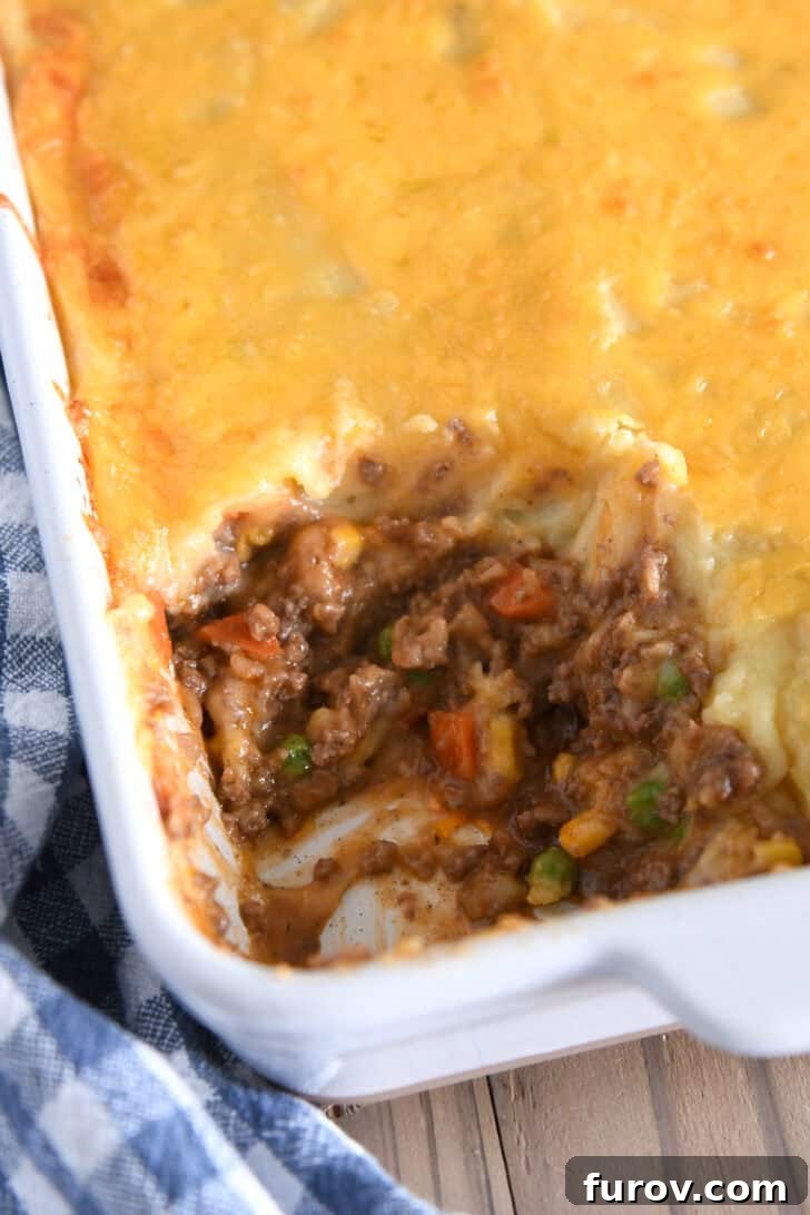 Rustic Meat and Potato Pie 7 Top-down view of a white casserole dish of baked Shepherd's Pie with a perfect helping scooped out, ready to be served.