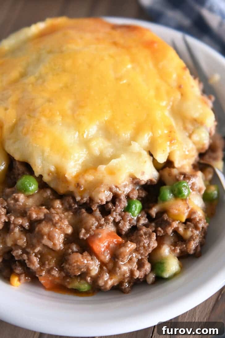 Rustic Meat and Potato Pie 8 A generous serving of Shepherd's Pie in a white bowl, showcasing the delicious layers of beef, vegetables, and cheesy mashed potatoes.