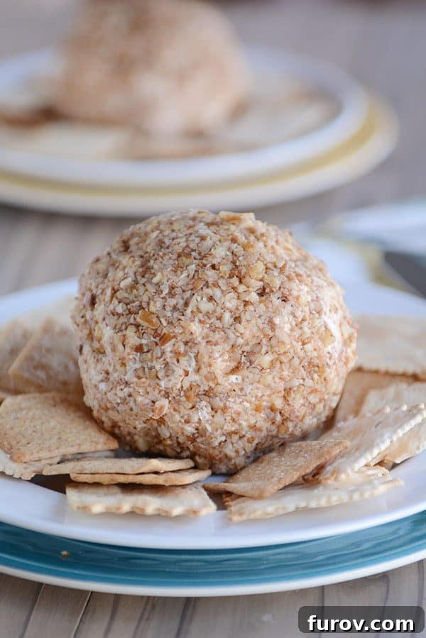 Pecan crusted cheeseball surrounded by crackers.