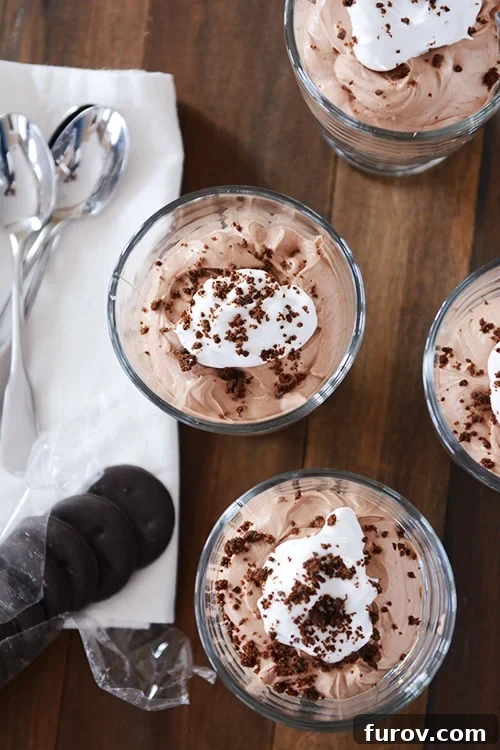 Top view of chocolate cheesecake desserts topped with whipped topping and a Thin Mint cookie.