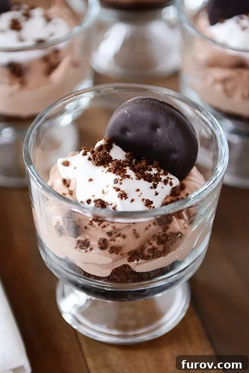 Small glass dishes full of a Thin Mint chocolate cheesecake dessert, showing layers.