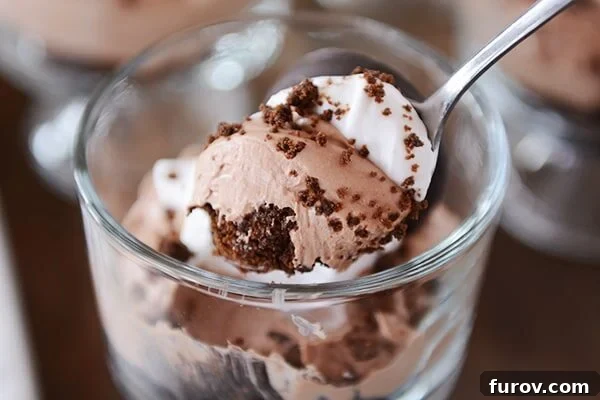 A spoon taking a bite out of a chocolate mint cheesecake dessert, showing the creamy texture.