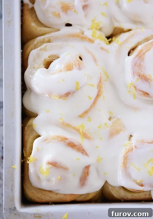 Bright Lemon Sticky Buns with Zesty Cream Cheese Glaze 2 Lemon sticky buns with glaze and lemon zest in metal pan, ready to be served.