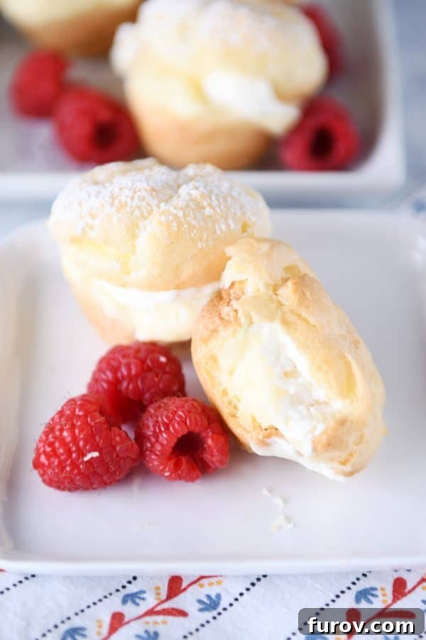 A delicious cream puff with a bite taken out, revealing its creamy interior, beautifully arranged on a white plate with fresh raspberries.