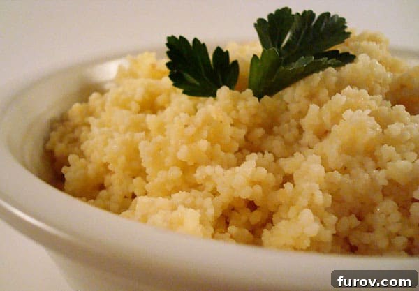 A white bowl filled with cooked, fluffy couscous, garnished with a fresh sprig of parsley on top.