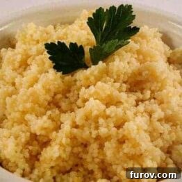 A close-up of fluffy cooked couscous in a white bowl, ready to serve.