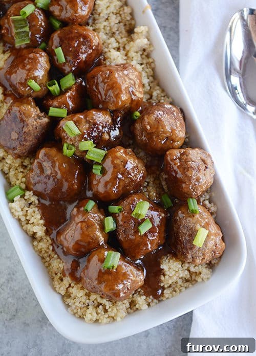 Top view of a white casserole dish full of rice topped with teriyaki coated meatballs.