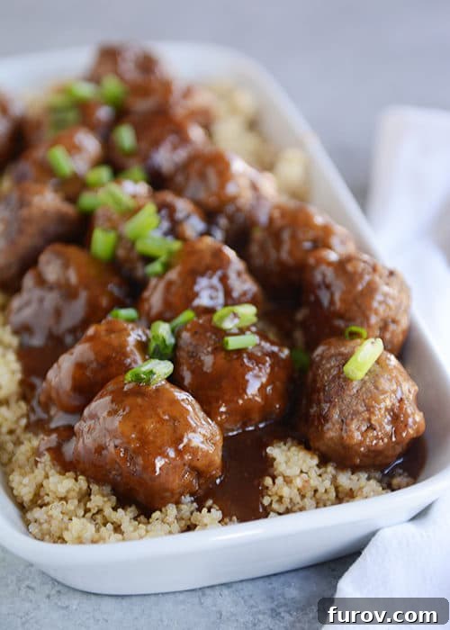A white casserole dish full of rice and meatballs covered in a teriyaki sauce.