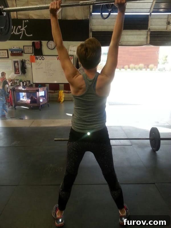 A lady lifting a barbell of weights over her head. 