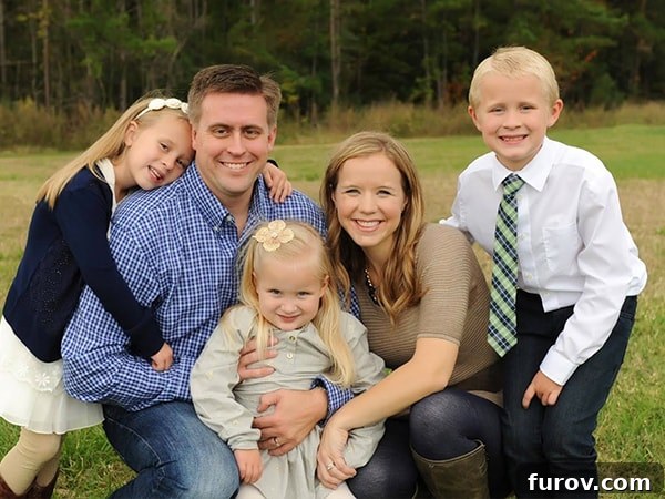 A Mom, Dad, and three small kids posing for a picture, smiling broadly.