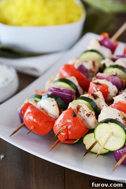 Zesty Greek Chicken Skewers with Cool Tzatziki 2 A white platter with grilled chicken and vegetable Greek kebabs, showcasing vibrant colors and enticing grill marks.