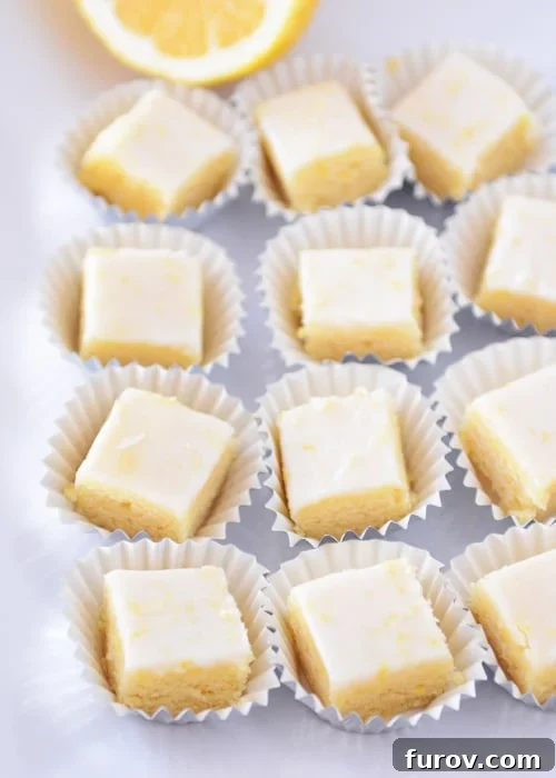 Top view of perfectly iced lemon brownies neatly arranged in small muffin cups, glistening with glaze.
