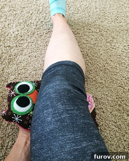 Runner applying an ice pack (owl rice bag) to her hamstring for recovery.