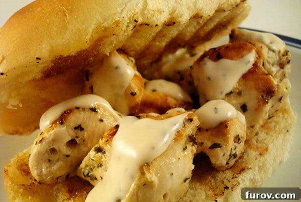 Close-up of a chicken spiedie sandwich, showcasing the grilled chicken pieces and creamy sauce on a fresh hoagie bun.
