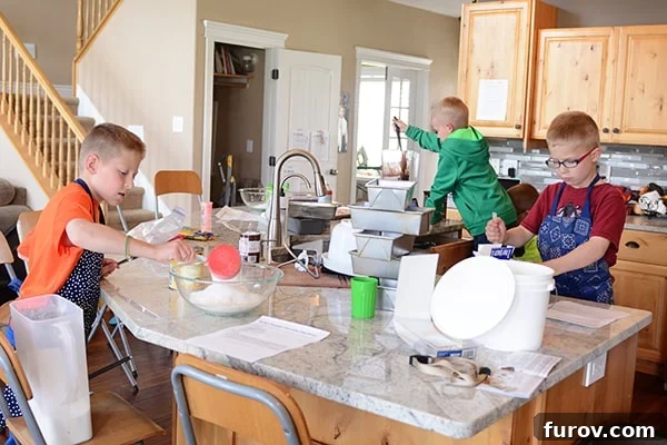 Three little boys all cooking in a kitchen together.