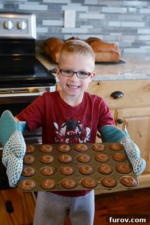 Little boy holding a pan of cooked muffins.