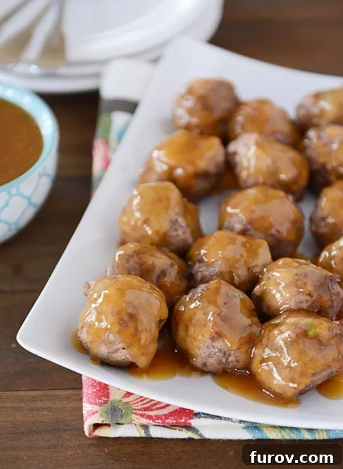 Sweet & Savory Orange Glazed Meatballs 2 A white platter with cooked meatballs covered in an orange glaze.