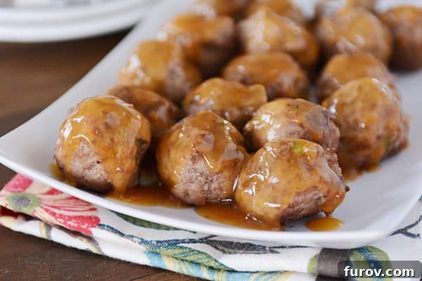 Sweet & Savory Orange Glazed Meatballs 5 A white platter of meatballs with an orange glaze poured over the top.