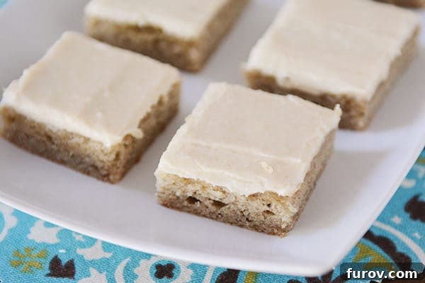 A elegant white platter filled with freshly baked and iced banana bars, showcasing their golden hue and inviting texture.