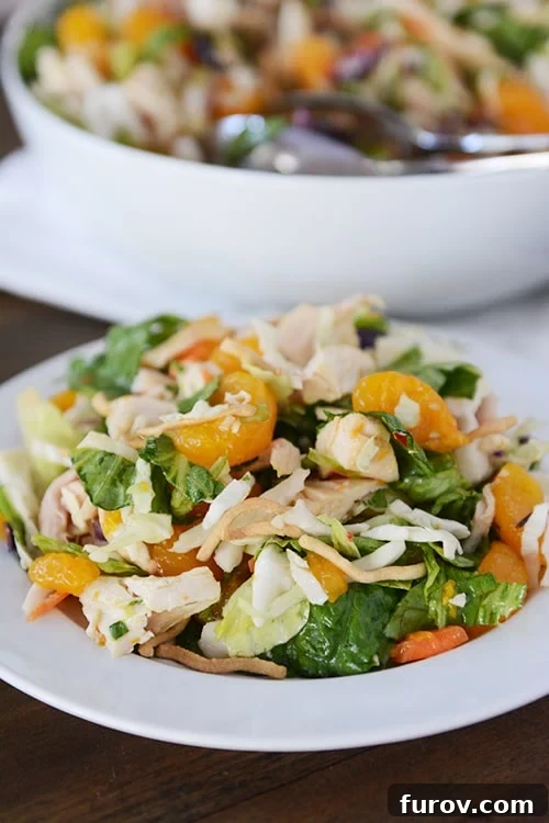 A beautifully arranged individual serving of mandarin orange chicken salad on a white plate, ready to be enjoyed.