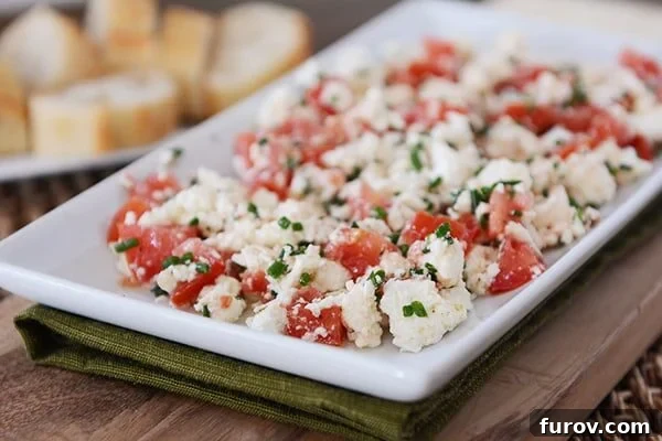 White tray full of a Greek feta tomato dip, artfully arranged and ready to be served.