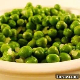 A dish of perfectly cooked buttery peas with thyme, garnished and ready to serve.