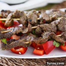 Quick and Easy Thai Beef Satay 4 Close-up of three grilled Thai Beef Satay skewers on a white dish, ready for serving.