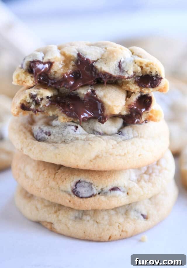 Stack of three soft chocolate chip cookies with two half cookies on top.