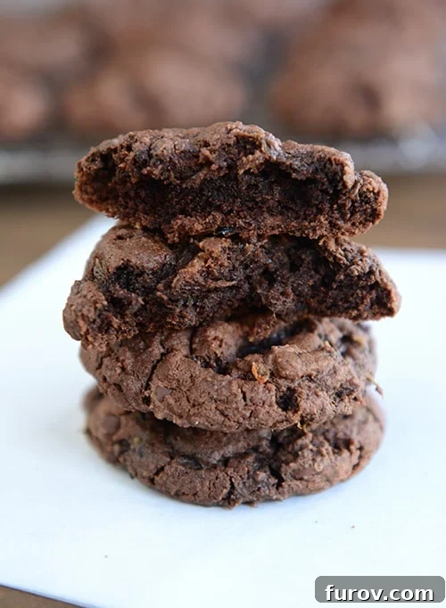 Three Triple Chocolate Zucchini Cookies stacked, with a bite taken out of the top two, revealing a soft, rich interior.