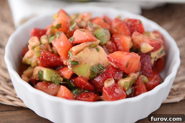 A white ramekin brimming with fresh, chunky strawberry avocado salsa, showcasing the vibrant colors and appealing texture.
