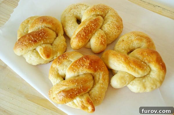 Pillowy Soft Homemade Pretzels 15 A top-down view of four soft, perfectly salted pretzels arranged on a white ceramic plate, ready to be enjoyed.