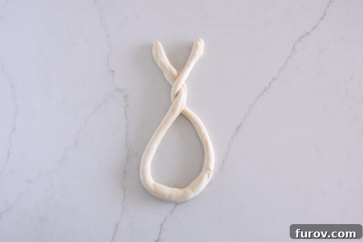 Pillowy Soft Homemade Pretzels 9 The process of forming a long, thin rope of pretzel dough into a pretzel by carefully twisting the ends together twice.