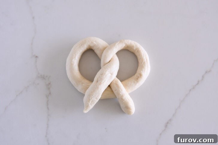 Pillowy Soft Homemade Pretzels 10 A perfectly shaped piece of dough ready to be baked into a soft pretzel, displaying the classic knot.